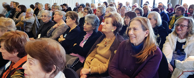A shot of an audience seated in rows, looking with interest at something 
